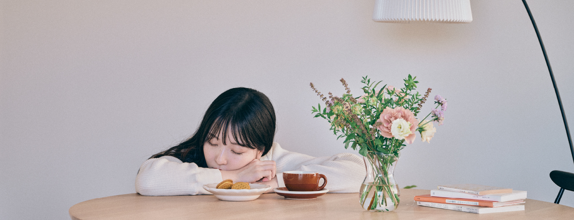 女性がテーブルに伏せて居眠りしている様子