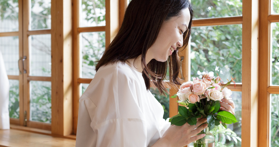 女性が窓辺で花を持っている様子